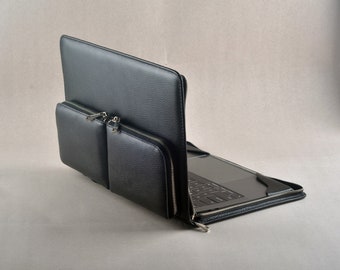 Może przedstawiać: Czarna skórzana torba na laptopa z kieszenią zapinaną na zamek błyskawiczny z przodu. Torba jest otwarta, a wewnątrz widoczny jest laptop.