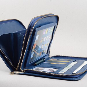 May include: A blue leather zippered case with a clear plastic window for a tablet, multiple card slots, and a pen holder.