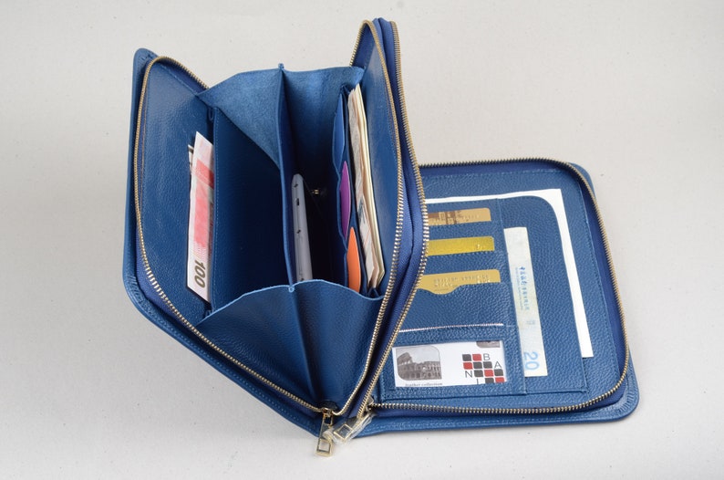 May include: A blue leather zippered wallet with multiple compartments for cash, cards, and a phone. The wallet is open and the interior is visible.