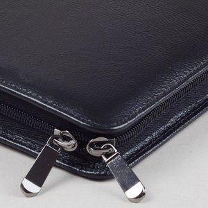 May include: A black leather zippered portfolio with two silver zipper pulls.
