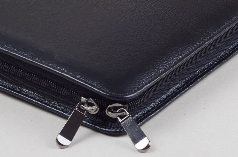 May include: A black leather zippered portfolio with two silver zipper pulls.