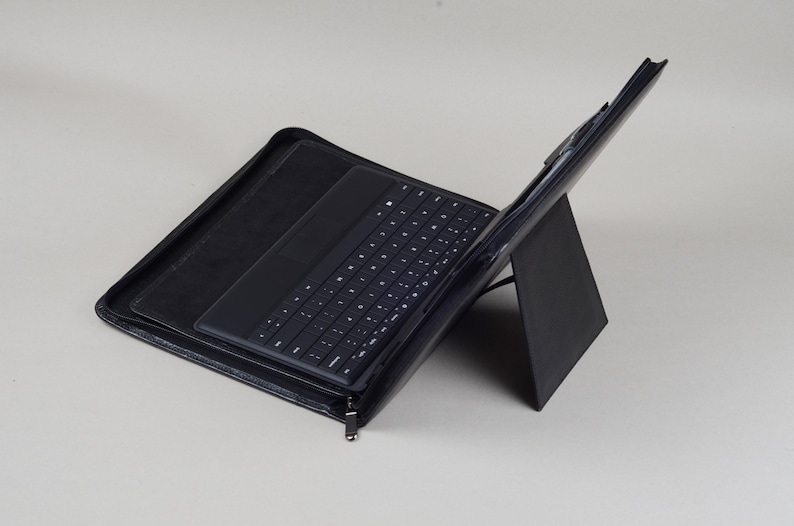 May include: A black leather case with a built-in keyboard and a stand for a tablet or laptop.