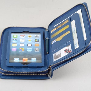 May include: A blue leather zippered case with a tablet computer inside. The case has multiple pockets and slots for cards, cash, and a pen.