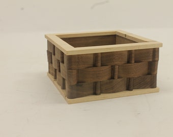 Square wooden basket that looks like it was woven. The basket makes a great storage spot for small items at 5 inches square.