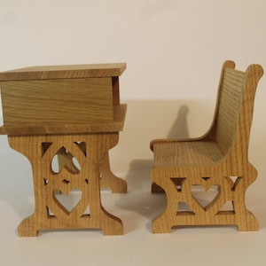 May include: A wooden desk and chair set with heart-shaped cutouts in the legs. The desk has a small drawer and the chair has a high back.