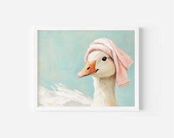 May include: A framed print featuring a whimsical illustration of a white goose wearing a pink towel on its head. The goose has an orange beak and is set against a light blue background. The artwork has a soft, painterly style.