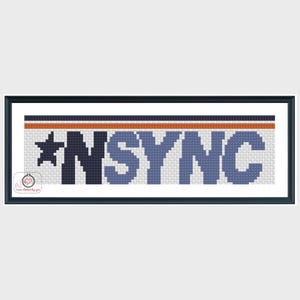 Op de afbeelding: Een ingelijst kruissteekkunstwerk met het woord "NSYNC" in blauwe en donkerblauwe blokletters, met een ster. Een horizontale streep in oranje en marineblauw accentueert de bovenkant. Het stuk is ingelijst in een zwart frame.