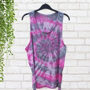 A tie-dye tank top with a pink, gray, and white swirl pattern. The tank top has a scoop neck and is made of a soft, comfortable fabric.