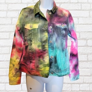 May include: A colourful tie-dye denim jacket, featuring a mix of pink, yellow, green, and blue hues. The jacket has a classic design with button fastenings, chest pockets, and a collared neckline. The jacket is displayed on a white mannequin.