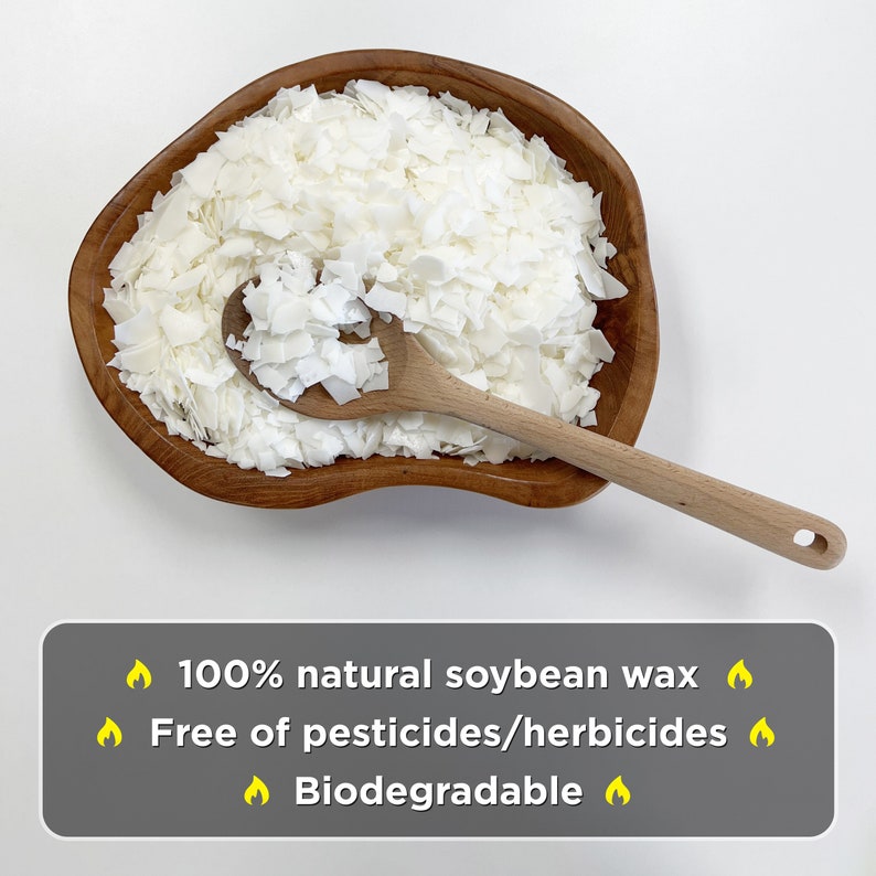 Puede incluir: Un bol de madera lleno de copos de cera de soja blanca. La cera es 100% natural, libre de pesticidas y herbicidas, y biodegradable. Una cuchara de madera descansa sobre los copos de cera.