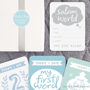 May include: A set of blue and green baby milestone cards with white text. The cards feature phrases like "Today I am 2", "Today I said my first word", and "Today is my first Ramadan". The cards also include a card that says "Salam world" with space to write in the date, time, weight, and length of the baby. The cards are part of a set called "Muslim Baby Milestone Cards".