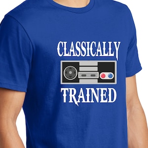 May include: A royal blue t-shirt with a white graphic of a classic video game controller and the text "Classically Trained".
