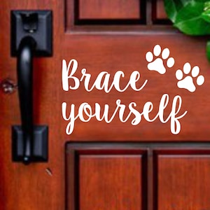 May include: White vinyl decal with the text "Brace yourself" and two paw prints on a wooden door.