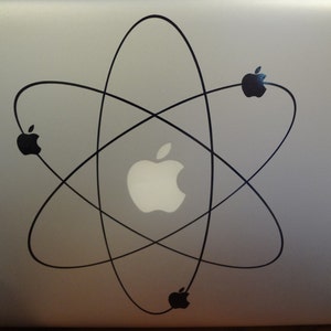 May include: A silver laptop with a black atom symbol sticker featuring an apple logo in the center. The sticker has four black apple logos on the ends of the atom symbol.