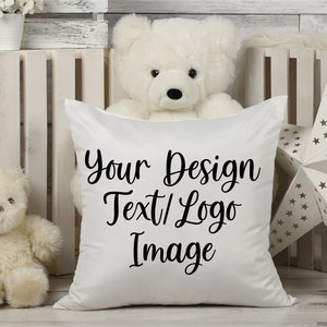May include: White pillow with black text that says "Your Design Text/Logo Image". The pillow is sitting on a white wooden surface with a white teddy bear behind it.