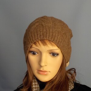 Cable design unisex beanie hat, hand-knit from rare breed Castlemilk Moorit wool at Roses Workshop. Shown with the welt turned down on a female model head. Natural undyed toffee brown pure British wool.