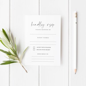 Minimalist printed RSVP card with the phrase “Nothing Fancy Just Reply!” in black modern typography, designed with fill-in-the-blank details for guest names, attendance, acceptance, dietary needs, and more. The card is placed on a white wooden background styled with white ranunculus flowers, gold vintage scissors, silk ribbon, and wooden spools – ideal for casual weddings, elopements, and budget-friendly celebrations with a simple, modern touch.