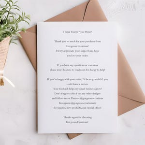 Minimalist printed RSVP card with the phrase “Nothing Fancy Just Reply!” in black modern typography, designed with fill-in-the-blank details for guest names, attendance, acceptance, dietary needs, and more. The card is placed on a white wooden background styled with white ranunculus flowers, gold vintage scissors, silk ribbon, and wooden spools – ideal for casual weddings, elopements, and budget-friendly celebrations with a simple, modern touch.
