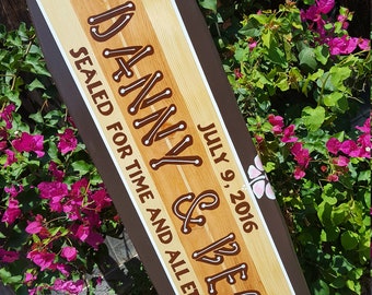 May include: A wooden surfboard painted with the names "Danny & Becky" and the date "July 9, 2016". The surfboard is decorated with flowers and the text "Sealed for time and all eternity".