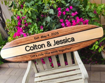 Puede incluir: Un letrero de madera con forma de tabla de surf con el texto "Est. May 4, 2025 Colton & Jessica Let's ride this wave together".