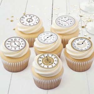May include: Six cupcakes with white frosting, each topped with a clock face design. The clock faces have different styles, with black and gold details. The cupcakes sit on a white surface with gold star confetti.