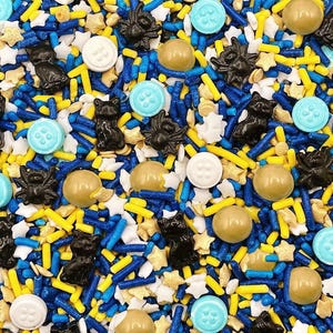 May include: A mix of edible sprinkles featuring black cat and spider shapes, light blue and white button-shaped candies, gold metallic spheres, and small white stars, combined with blue and yellow rod-shaped sprinkles for a decorative topping.