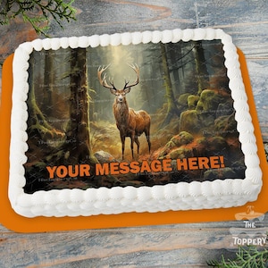 May include: A rectangular cake with white frosting and an orange base. The cake features an edible image of a deer in a forest scene. Text on the cake reads "YOUR MESSAGE HERE!" in orange. The cake is decorated with white frosting around the edges.