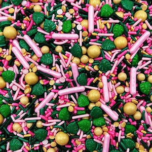 May include: A colorful mix of sprinkles, including pink, green, and yellow shapes. The sprinkles include pink sticks, green leaf shapes, and small yellow balls. The background is a mix of pink, green, and yellow sprinkles.