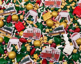May include: A festive holiday sprinkle mix featuring edible shapes including red and white vintage campers, station wagons with Christmas trees on top, red and white winter hats, gold metallic spheres, red gift boxes, and green trees.