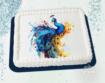 May include: A rectangular cake with white frosting and a decorative border. The cake is topped with a colorful watercolor image of a peacock with blue, orange, and yellow hues. The cake sits on a dark blue base.