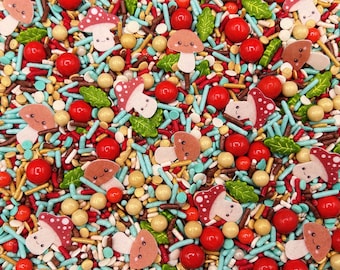 May include: A colorful mix of edible sprinkles featuring red and white mushroom-shaped sugar pieces with smiling faces, green leaf-shaped sprinkles, shiny red round candy balls, light blue rod-shaped sprinkles, and small tan round beads.