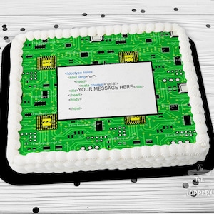 May include: A rectangular cake with white frosting and a green circuit board design. A white rectangle in the center has the text "YOUR MESSAGE HERE" and HTML code. The cake sits on a black tray.