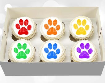 May include: A set of six cupcakes arranged in a white cardboard box. Each cupcake features a white circular topper with a solid colored paw print graphic in red, orange, yellow, green, blue, and purple, respectively, atop white frosting.
