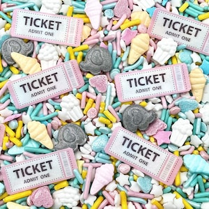 May include: A close-up of a variety of colorful sprinkles, including pastel pink, blue, and yellow. There are also small white and gray sprinkles shaped like ice cream cones, cupcakes, and clouds. The sprinkles are arranged in a random pattern and are scattered across the surface of the image. There are also several pink tickets with the text "TICKET ADMIT ONE" printed on them.