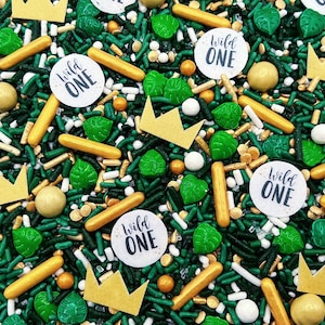 May include: Green, gold, and white sprinkles with a "Wild One" theme. The sprinkles include small green leaves, gold crowns, gold and white sprinkles, and round white circles with the text "Wild One" in black.