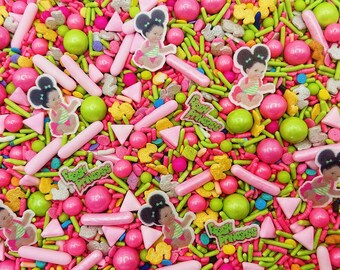 May include: A colorful mix of edible sprinkles featuring pink and lime green rod-shaped sprinkles, round gumballs, small triangles, and sugar shapes. The mix includes printed edible toppers of a baby with buns and the text Fresh Princess.