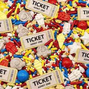 May include: A colorful assortment of candies and sprinkles, including red, yellow, blue, and white shapes. Several tickets with the text "TICKET ADMIT ONE" are scattered throughout the image. The candies include stars, ice cream cones, and popcorn shapes.