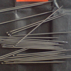 May include: A close-up image of a bundle of silver sewing needles. The needles are arranged in a random pattern, with some needles overlapping others. The needles are sharp and pointed, and they are all the same size.