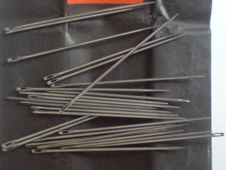 May include: A close-up image of a bundle of silver sewing needles. The needles are arranged in a random pattern, with some needles overlapping others. The needles are sharp and pointed, and they are all the same size.