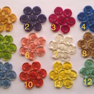 May include: Twelve sets of plastic buttons in various colours, each set containing 12 buttons. The buttons are translucent and have a raised design. The sets are numbered 1 through 12.