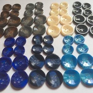 May include: Assortment of 40 round buttons in various colors and patterns. The buttons are made of plastic and have a swirl design. The colors include brown, gray, white, blue, and black.