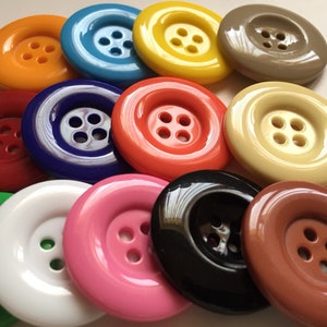 Può includere: Assortimento di 14 bottoni di plastica colorati con quattro fori ciascuno. I bottoni sono di vari colori, tra cui rosso, arancione, giallo, verde, blu, viola, rosa, marrone, nero e bianco.