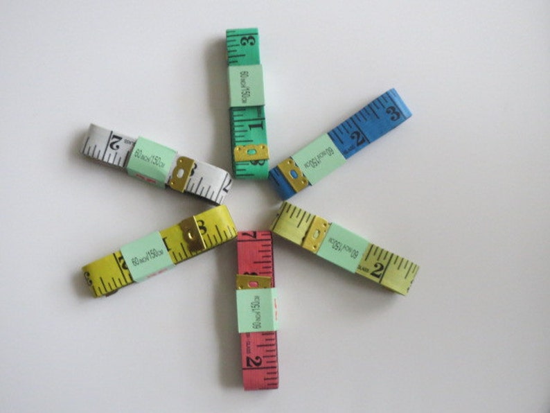 May include: Five different colored measuring tapes with green, blue, yellow, red, and white labels. The labels have the text "80 inch/150 cm" and "Black 75cm".