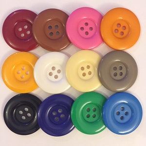 May include: Twelve round plastic buttons in various colors, including red, brown, pink, orange, yellow, white, beige, gray, black, blue, green, and light blue. Each button has four holes.