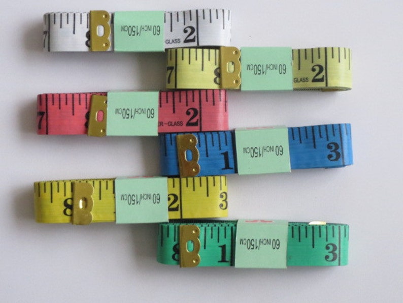 May include: Five different colored measuring tapes with a black and white measuring scale. The tapes are labeled with "60 INCH/150CM" and "GLASS".