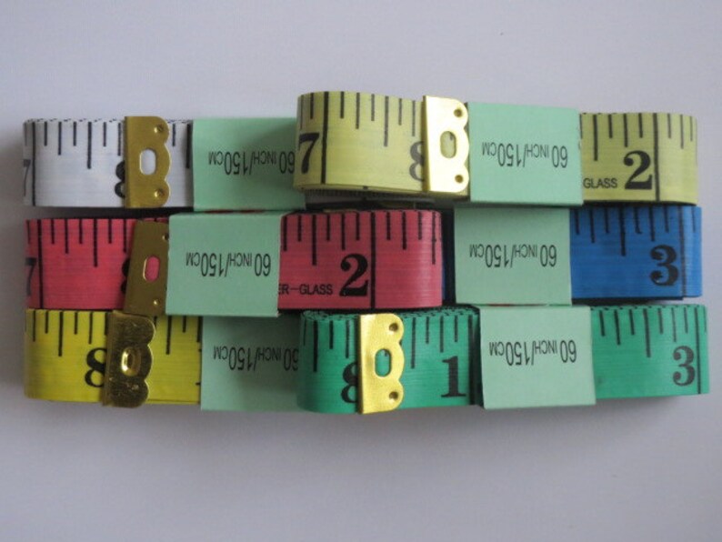 May include: A set of ten measuring tapes in various colors, including yellow, green, blue, red, and white. Each tape is 60 inches or 150 centimeters long. The tapes have a metal end with a loop for hanging.