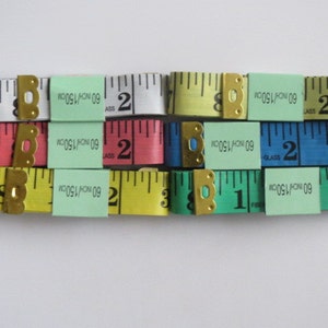May include: A set of six measuring tapes with different colored cases. The tapes are labeled with "60 INCH/150CM" and have numbers printed on them. The tapes are arranged in two rows of three.