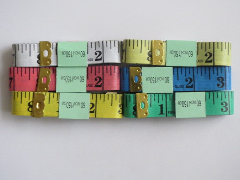 May include: A set of six measuring tapes with different colored cases. The tapes are labeled with "60 INCH/150CM" and have numbers printed on them. The tapes are arranged in two rows of three.