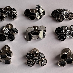 Peut inclure: Assortiment de boutons en métal noir et argent avec différents motifs, notamment des rayures, des fleurs et des motifs géométriques.
