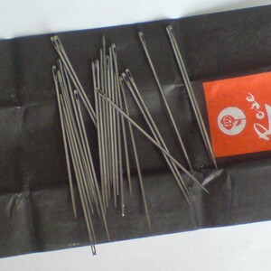 May include: A pack of silver sewing needles labeled "Rose Hand Sewing Needles No. 1" on a black background.